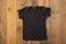Layout Black children`s t-shirt on wooden background.Mockup .Flat lay
