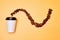 Layout of coffee beans in wavy line on yellow background with white disposable coffee cup