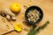 Layout with dry chamomile flowers in clay bowl, fish oil capsule, lemon, ginger, calendula in wooden spoon, and fir tree at wooden