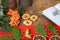 Layout with a warm red scarf, rowan, dried apples, oranges, candlesticks , oak leaves and blacnot on a brown surface