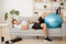 Laziness and workout. Tired guy sleeping on couch with dumbbell and fitness ball