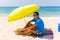 Lazing man in sun under solar umbrella on towel enjoy the lazy time on the beach