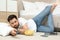 Lazy man with bowl of chips watching TV while lying on floor at home