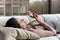 Lazy young lady rest on couch after wakeup using cellphone