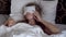 Lazy young woman with blindfold on eyes wakes up in her bed late in the morning