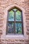 Leaded gothic window in rock building on University campus reflecting trees and nature