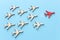 Leadership concept with airplanes on blue wooden background. One red leader flays ahead others.