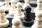Leadership, diversity and individuality concept with black pawn surrounded by many white pawns on crowded chess board