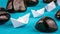 Leadership lead further white paper ships between stones on blue background. Right to left moving.