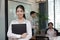Leadership young Asian business woman standing and smiling with colleage in meeting room background.