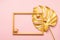 Leaf of a tropical plant frame Christmas balls serpentine painted gold pink background. Art concept. Festive minimalism.