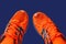 Leaky orange sneakers with protruding fingers isolated on a dark blue background