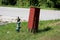 Leaning dark red metal fire department box locked with padlock next to dilapidated rusted light blue fire hydrant