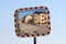 Leaning new convex rectangular traffic mirror with red and white striped frame with row of suburban family houses in reflection