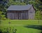 Leaning wooden barn at edge of grass.