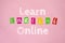 LEARN ENGLISH ONLINE phrase isolated on pink. Study at home flat lay