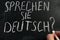 Learn German. Sprechen Sie Deutsch sign on a blackboard