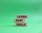 Learn new skills symbol. Concept words Learn new skills on wooden blocks. Beautiful green background. Business and Learn new