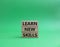 Learn new skills symbol. Concept words Learn new skills on wooden blocks. Beautiful green background. Business and Learn new