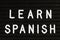 Learn Spanish language, modern looking sign on black background