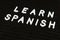 Learn Spanish language, modern looking sign on black background