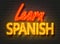 Learn Spanish, neon sign on brick wall