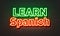 Learn Spanish neon sign on brick wall background.