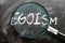 Learn, study and inspect egoism - pictured as a magnifying glass enlarging word egoism, symbolizes researching, exploring and