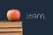 Learn written on blackboard with apple and books