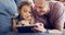 Learning about the ways of a wireless world. a cute little girl using a digital tablet with her father on the sofa at