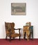 Leather armchair, vintage round table and painting on red carpet