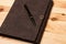 Leather-bound business notebook with a Parker pen on wooden background. Business concept