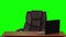 Leather business chair rotating near a table with a laptop. Green screen. Slow motion