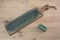 Leather knife strop with green polishing compound on a wooden surface.