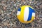 Leather multi-colored volleyball ball on a pebble beach background close-up.