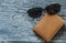 leather purse with sunglasses lying on a wooden table