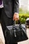 Leather suitcase in hand. Person in suit holding men bag