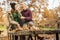 Leaves over a wood table in the park at first shot. Couple talking in the background