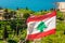 Lebanese red and white with green cedar tree flag waving on the  wind with sea in the background, Byblos, Lebanon
