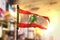 Lebanon Flag Against City Blurred Background At Sunrise Backlight