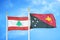 Lebanon and Papua New Guinea two flags on flagpoles and blue cloudy sky