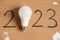 Led light bulb and written year 2023 on brown paper ,new technology in the new year