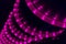 LED violet light string spiral over black pillar in club