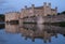 Leeds Castle in Kent UK, reflected in the surrounding moat, photographed in late afternoon on a clear crisp autumn afternoon.