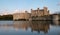 Leeds Castle in Kent UK, reflected in the surrounding moat, photographed in late afternoon on a clear crisp autumn day.