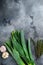 Leek stalks with herbs ingredients for coocing Braised Leeks, on grey textured background top view with space for text