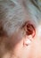 Left ear of a gray-haired elderly man with hearing loss, hearing problems, the concept of rehabilitation of old deaf people