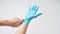 Left hand is pulling right hand with blue latex gloves on white background