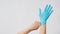 Left hand is pulling right hand with blue latex gloves on white background