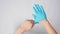 Left hand is pulling right hand with blue latex gloves on white background